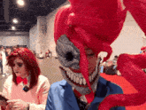a woman with red hair is looking at her phone next to a man with a mask on his face