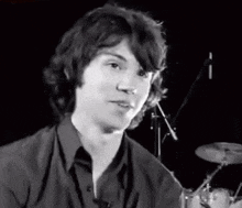 a black and white photo of a young man sitting in front of a microphone .