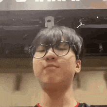 a young man wearing glasses is making a funny face in front of a computer monitor .