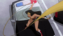 a woman in a wonder woman costume is standing on the hood of a police car