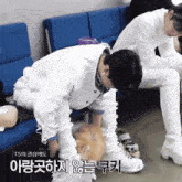 a man in a white jacket is kneeling down next to another man in white pants