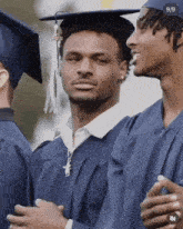 a man in a graduation cap and gown stands next to another man .