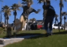 a man is jumping in the air in a park while another man watches .