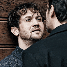 a man with a beard looks at another man