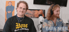two men are sitting in front of a microphone and one of them is wearing a black shirt that says bone