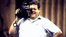 a man in a blue shirt is holding a camera in his hand .