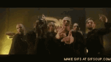 a group of men are dancing in a dark room with their hands in the air .