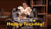 a man is sitting in a chair holding two dogs and says happy tuesday .