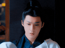 a young man with a ponytail is wearing a blue and white outfit