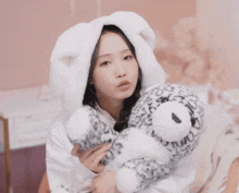 a woman wearing a white bunny hood holds a stuffed leopard