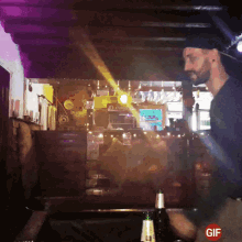 a gif of a man behind a bar with a bottle of corona