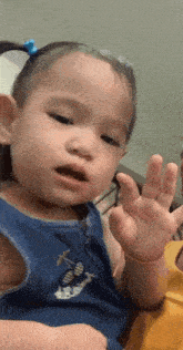 a little girl is wearing a blue tank top with a fish on it