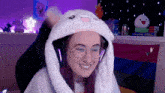 a woman wearing a bunny hat and glasses is smiling in front of a bisexual flag