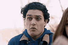 a man in a blue jacket is making a funny face while standing next to a woman .