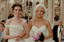 two women in wedding dresses are walking down the aisle together
