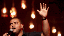 a man is singing into a microphone with his hand in the air