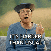a man wearing glasses and a hat says it 's harder than usual with his middle finger