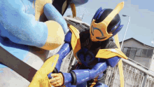 a man in a blue and yellow costume with the letter g on his chest
