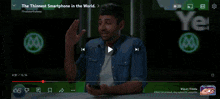 a man is holding a cell phone in front of a screen that says hold our thing on it