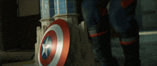 a captain america shield is being kicked by a person in black boots