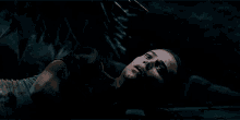 a woman in a tank top is laying on the ground in the dark
