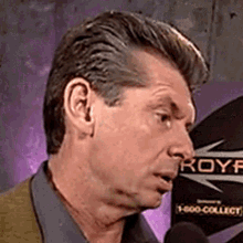 a man talking into a microphone with a sign behind him that says royf on it