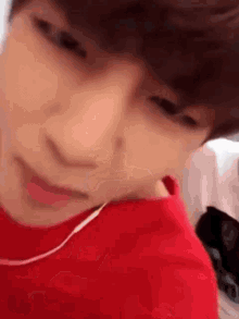 a close up of a person wearing a red shirt and earphones .