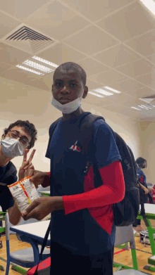 a young man wearing a mask holds a bag of chips