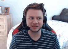 a man wearing a headset and a striped shirt looks at the camera