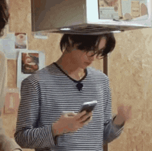 a man wearing glasses and a striped shirt is looking at his cell phone .