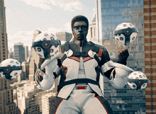 a man in a space suit is juggling three balls in front of a cityscape