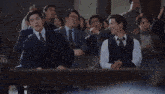 a man in a suit and tie is standing in front of a crowd .