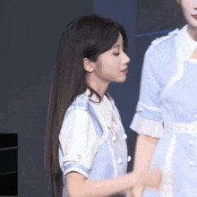 a woman in a blue dress is standing next to a woman in a white dress