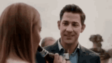 a man in a suit and tie is smiling at a woman in a white shirt .