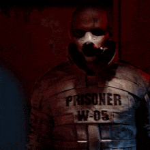 a man wearing a gas mask and a prisoner shirt