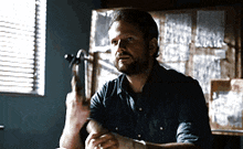 a man in a blue shirt is holding a gun in his hand