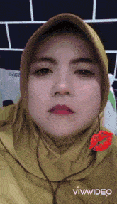 a woman wearing a hijab has a kiss on her lip and the word vivavideo is on the bottom