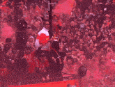 a man holding a trophy in front of a crowd with the word coca cola written on his shirt