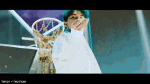 a person with blue hair is holding a basketball hoop in their hand .