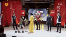 a group of people standing on a stage with a sign that says x