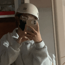 a person wearing a helmet and glasses takes a selfie with their phone