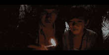 a man and a young boy are standing next to each other in a dark room .