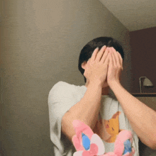 a man is covering his face with his hands while holding a stuffed animal ..