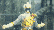 a white and gold power ranger is giving a thumbs up with his arms outstretched