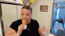 a woman wearing a bee headband drinks a can of beer