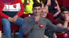 a man is holding a microphone in front of a crowd with the words en vivo on the bottom right