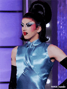 a woman wearing a blue dress and black gloves has a tattoo on her shoulder