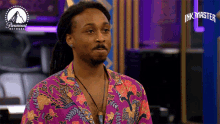 a man in a purple floral shirt is standing in front of a paramount network logo