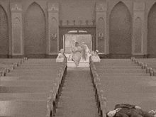 a group of people are walking down the aisle of a church with a man laying on the floor