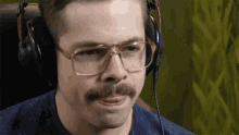 a man with glasses and a mustache is wearing a pair of headphones